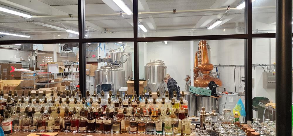 Tons of bottles and the distillery behind the tasting room bar at Sturgeon Spirits Distillery in Oshkosh, Wisconsin
